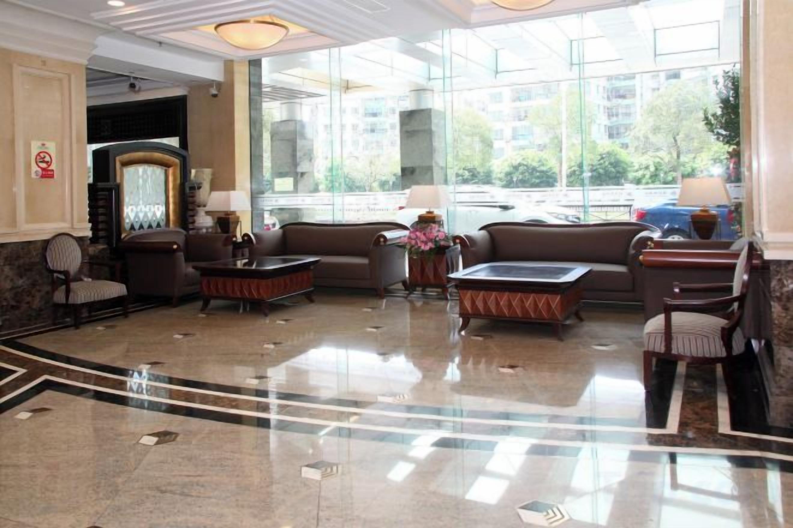 A hotel lobby with a reception desk, seating area, and large windows.