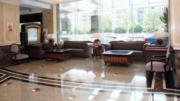 A hotel lobby with a reception desk, seating area, and large windows.