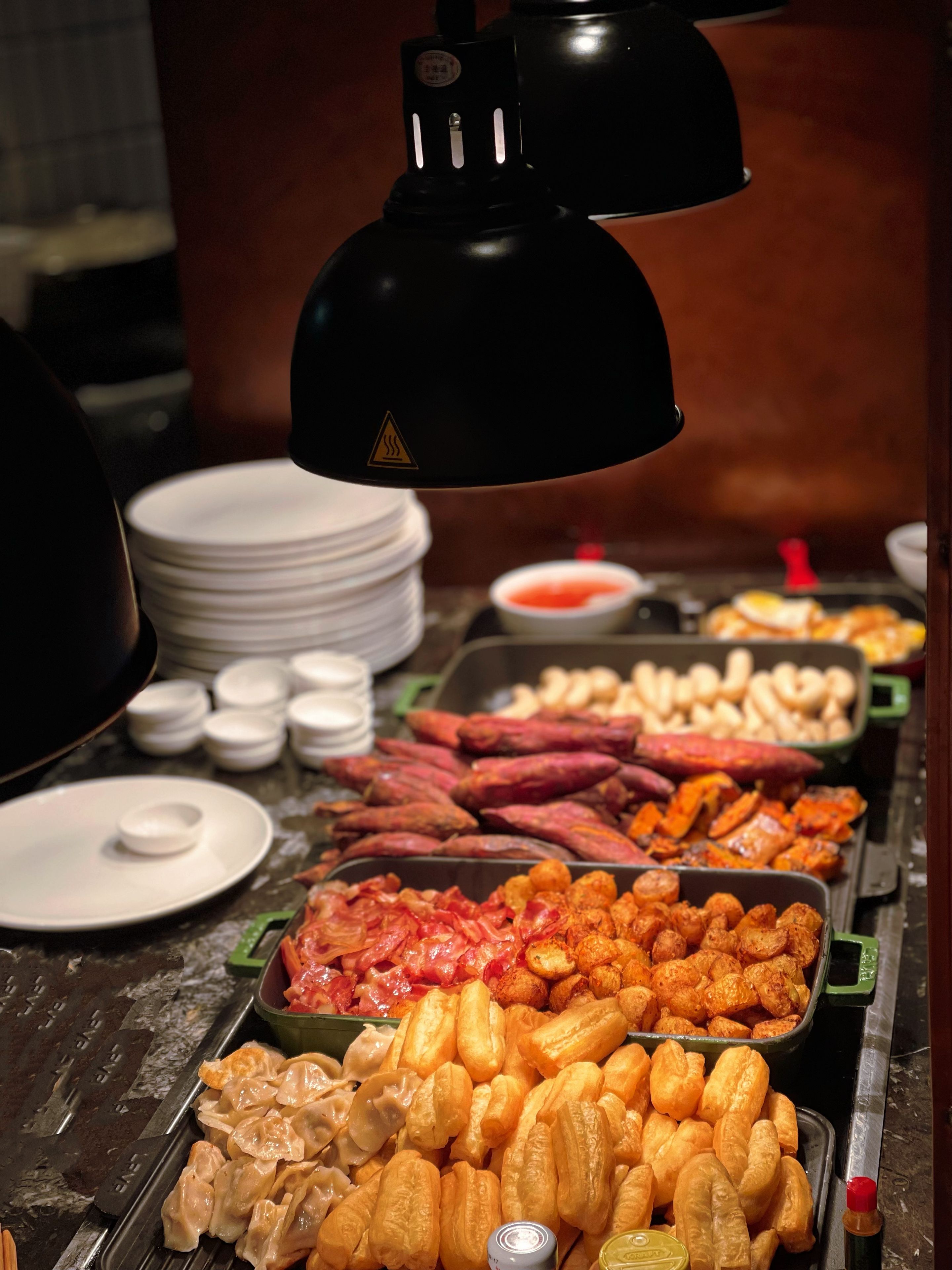 A buffet with various food items including sweet potatoes, meats, and dumplings.