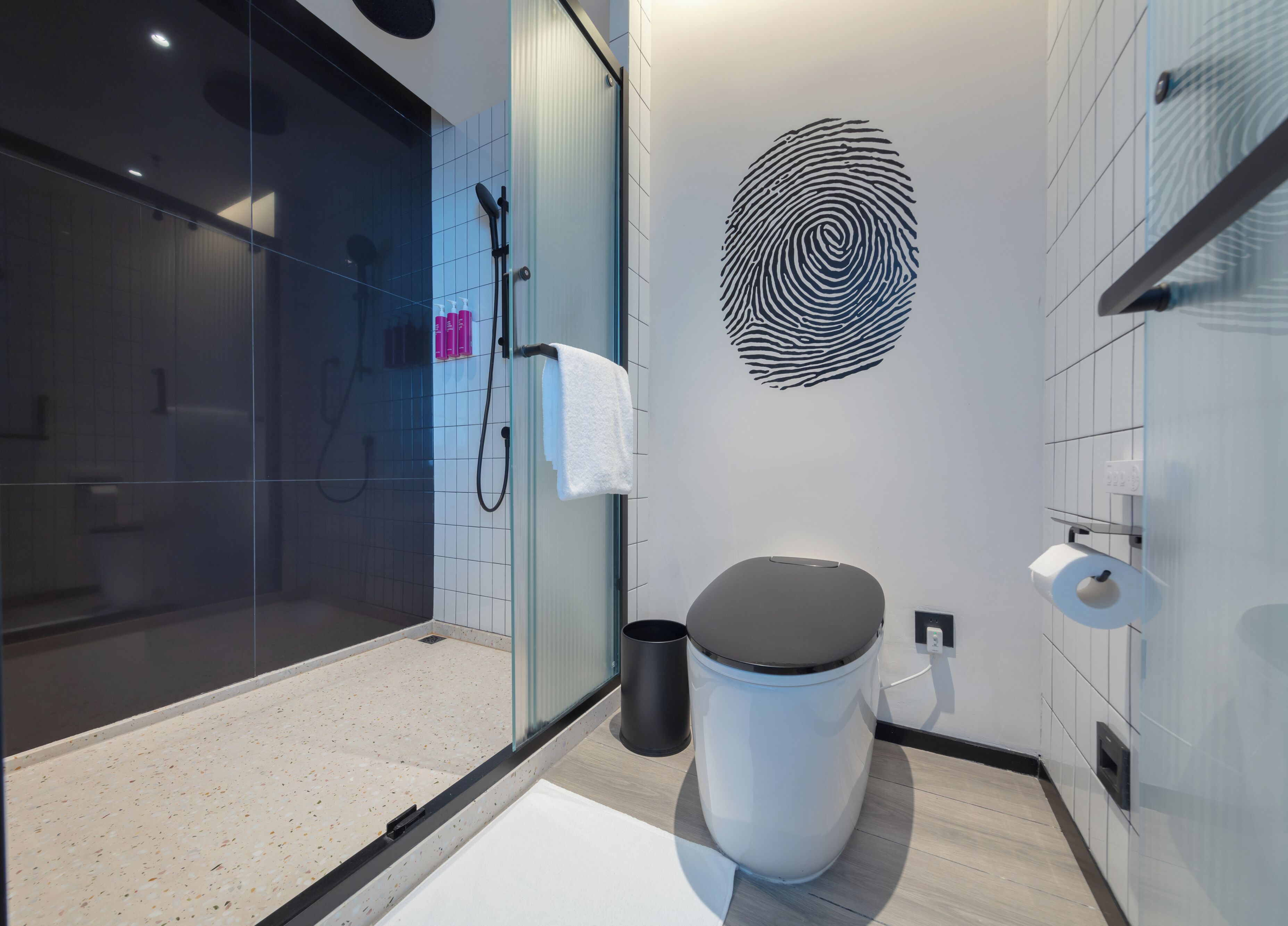 A modern bathroom with a glass shower enclosure, a toilet, and a wall-mounted sink.