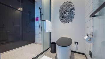 A modern bathroom with a glass shower enclosure, a toilet, and a wall-mounted sink.