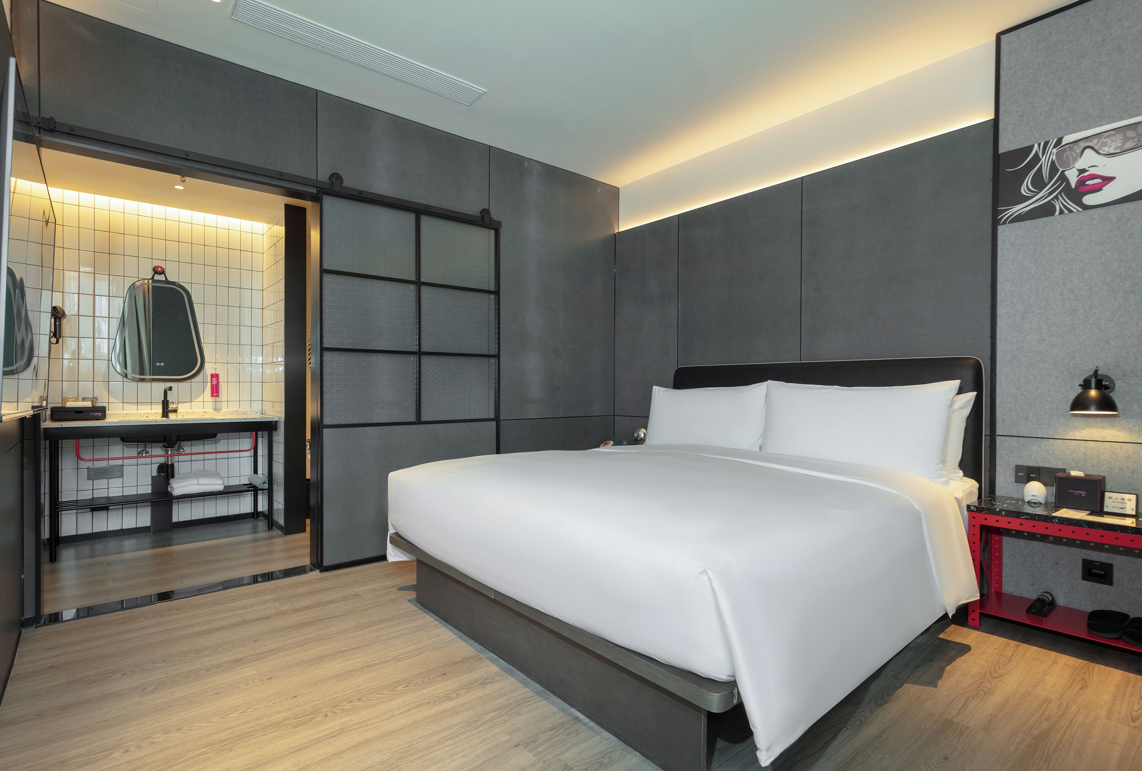 Een moderne hotelkamer met een groot bed, een ingebouwd bureau, een kaptafel met spiegel en een nachtkastje in het rood.