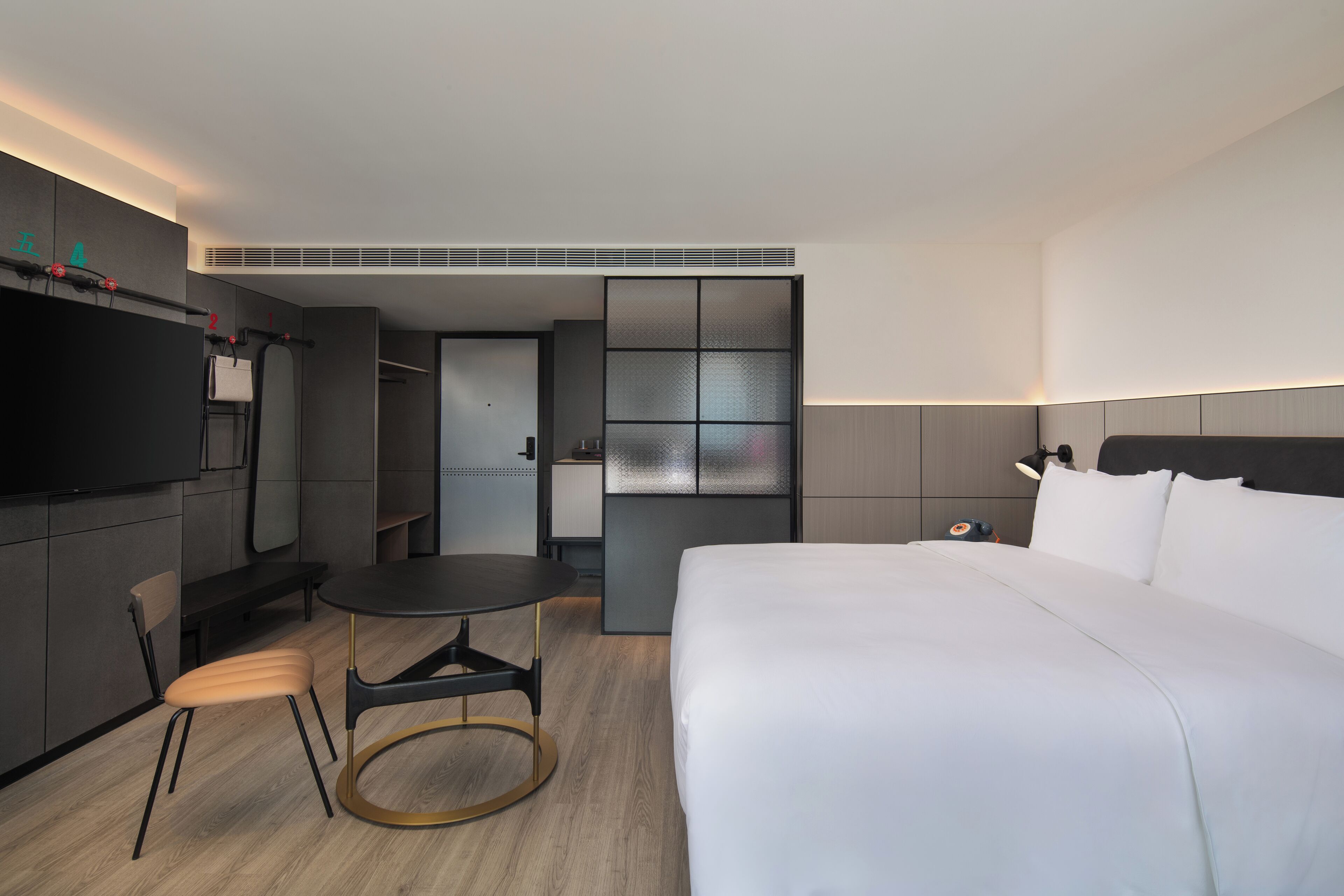 Een moderne hotelkamer met een groot bed, een eettafeltje, een stoel, een televisie en een inloopkast.