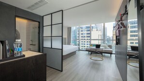 Una habitación de hotel moderna con una cama grande, un escritorio y una zona de estar con vistas a la ciudad.