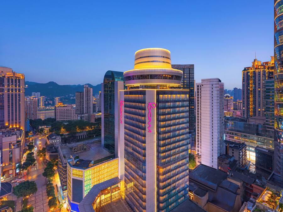 A high-rise building with a distinctive circular top, surrounded by other tall buildings in a cityscape.