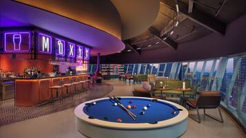 A modern bar area with neon signage, a pool table, and a city view.