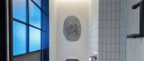 Une salle de bain moderne avec un motif représentant des empreintes digitales sur le mur, des toilettes et une poubelle.