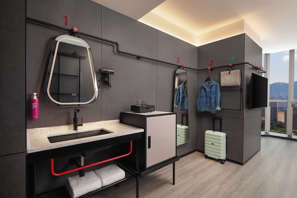 A modern bathroom with a large mirror, a sink, a towel rack, and a suitcase. - Moxy Chongqing (Chongqing)
