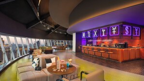 Un área de descanso moderna con bar, asientos y vista panorámica de la ciudad.