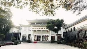 A traditional building with a central courtyard, a large wooden wheel, and a sign with Chinese characters. - Zhuhai Harmony Resort Hotel (Zhuhai)