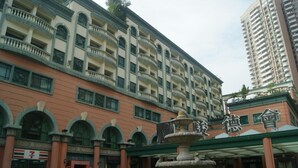 A multi-story hotel with a fountain in front, a 7-Eleven store, and a sign with Chinese characters. - Zhuhai Harmony Resort Hotel (Zhuhai)