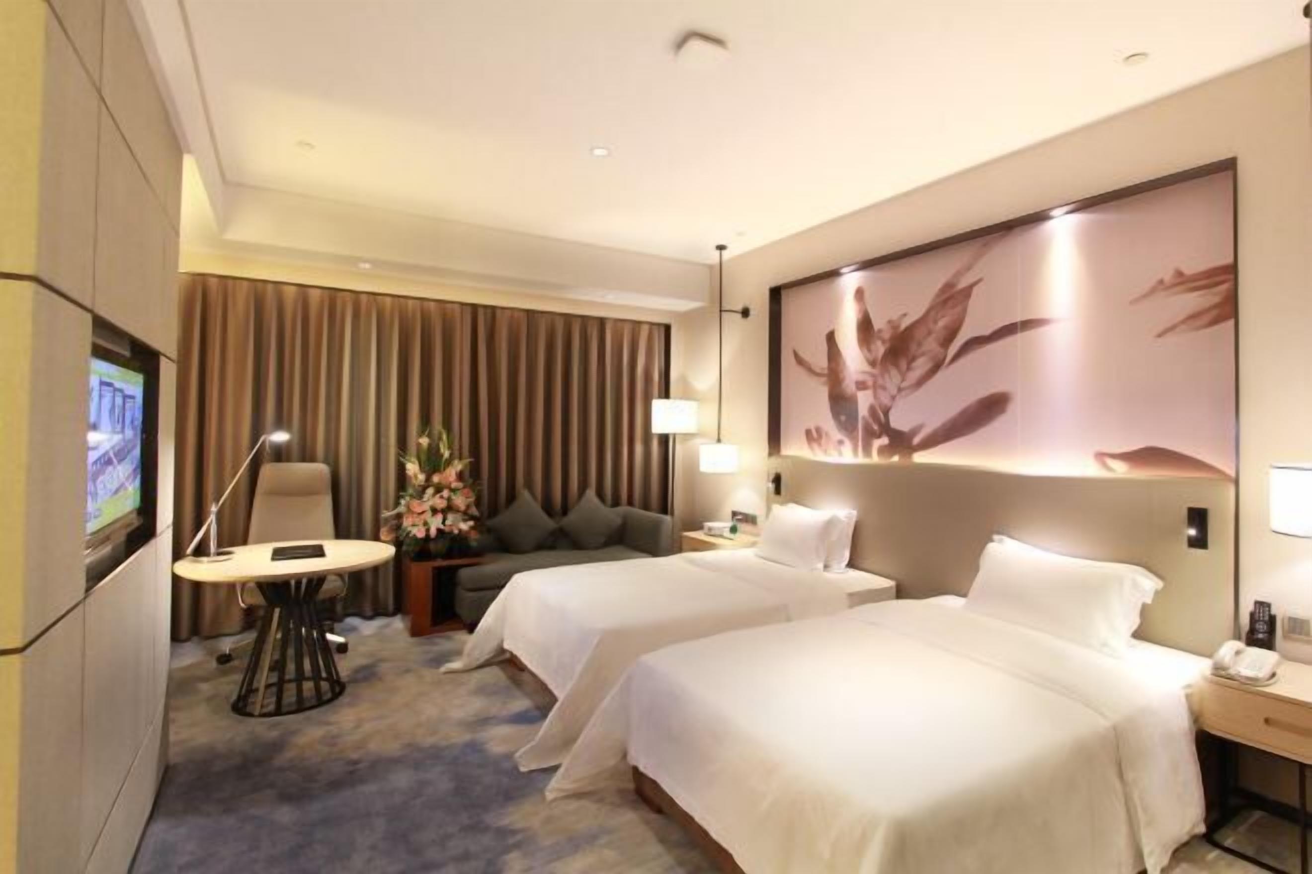 Habitación de hotel con dos camas, televisión, escritorio y lámpara.