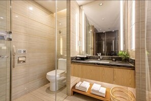 Une salle de bain moderne avec une douche à parois de verre, des toilettes, un lavabo avec un meuble-vasque en bois et un banc avec des serviettes.