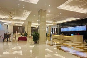 Un vestíbulo de hotel con una recepción, una pantalla grande y un piso pulido.