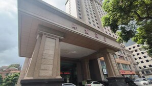 L’entrée d’un hôtel, dotée d’un large auvent et de colonnes, et sur laquelle on peut voir une enseigne avec des caractères chinois.