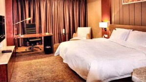 Une chambre d’hôtel avec un grand lit, un bureau avec un ordinateur, une chaise et un téléviseur.