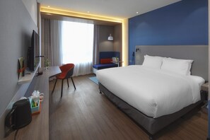 A hotel room with a large bed, a desk with a chair, a TV, and a window with curtains. - Holiday Inn Express Shanghai Chongming by IHG (Shanghai)