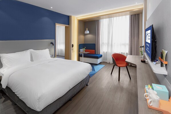 A hotel room with a large bed, a desk, a chair, a TV, and a window with curtains. - Holiday Inn Express Shanghai Chongming by IHG (Shanghai)