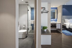 A modern bathroom with a toilet, shower, and sink. There is a plant on a shelf and a towel rack on the wall. - Holiday Inn Express Shanghai Chongming by IHG (Shanghai)