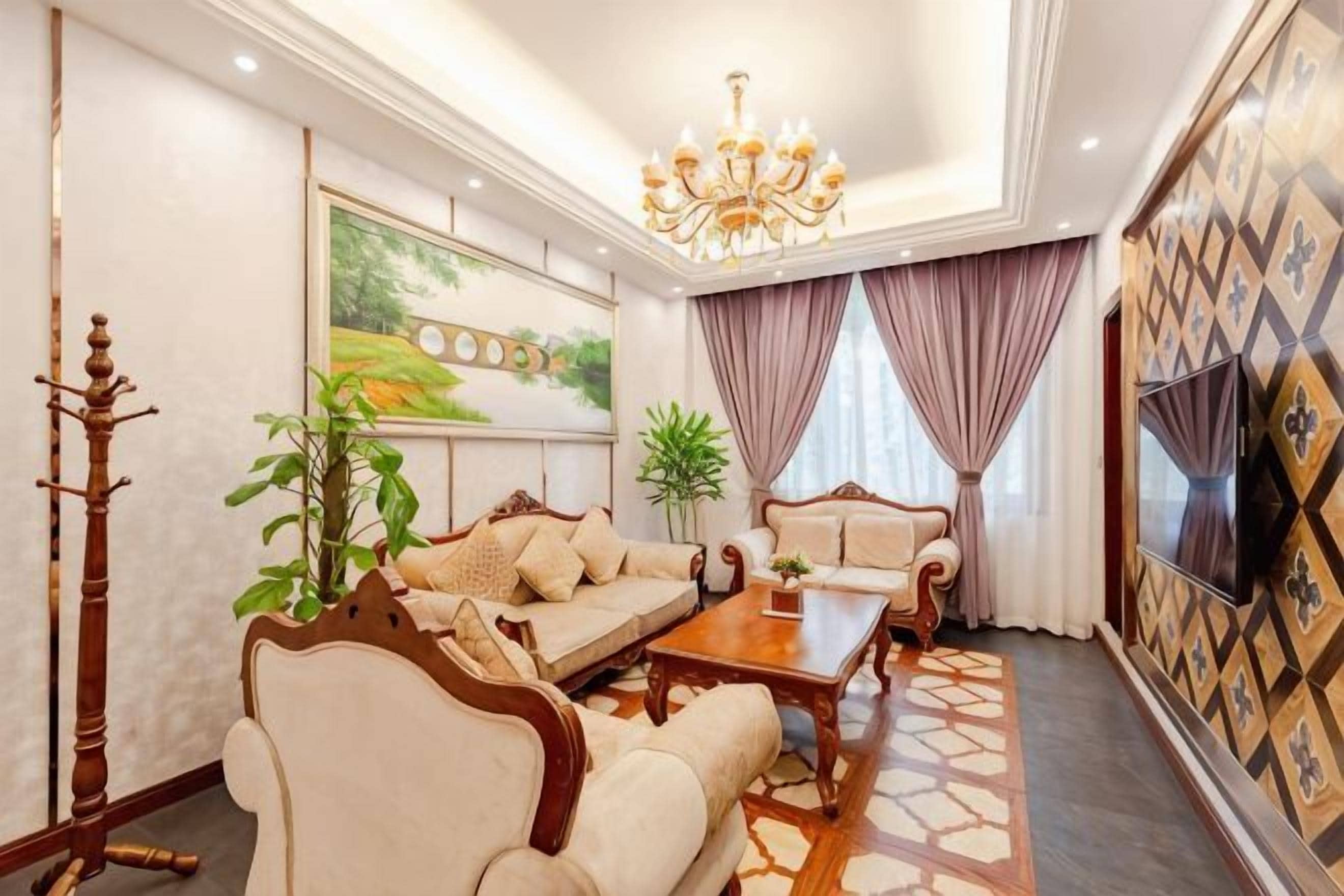 A well-lit living room with a sofa, armchairs, a coffee table, and a television.