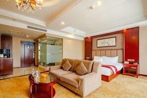 A hotel room with a sofa, a bed, a small table, a nightstand, and a wall-mounted artwork. - Lanting Hotel Qionglai High-speed Railway Station Branch (Chengdu)