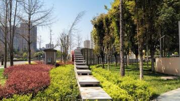 Un camí vorejat per vegetació i arbres que condueix a un edifici amb una construcció petita.