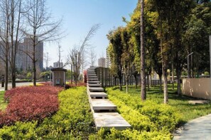 Een pad bekleed met begroeiing en bomen, dat leidt naar een gebouw met een klein bijgebouw.
