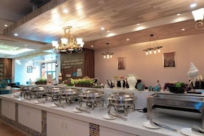 Een buffetopstelling met meerdere aanhalingstations, een koffieapparaat en een fruitpresentatie.