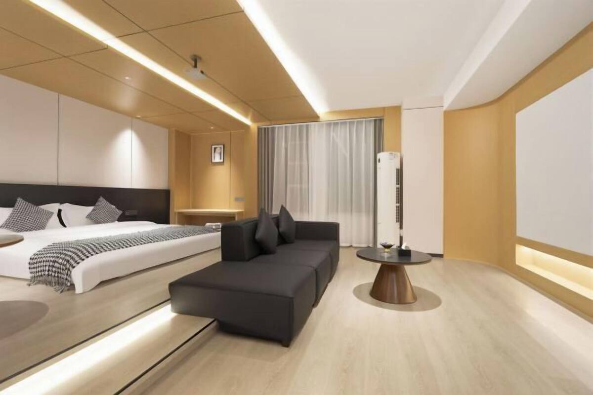 Una habitación de hotel moderna con una cama, un sofá, una mesita de noche y una lámpara de pie.