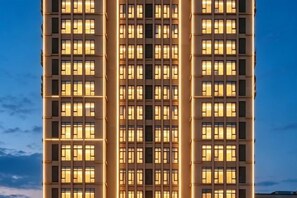 Un edificio alto con varios pisos y ventanas uniformemente iluminadas.