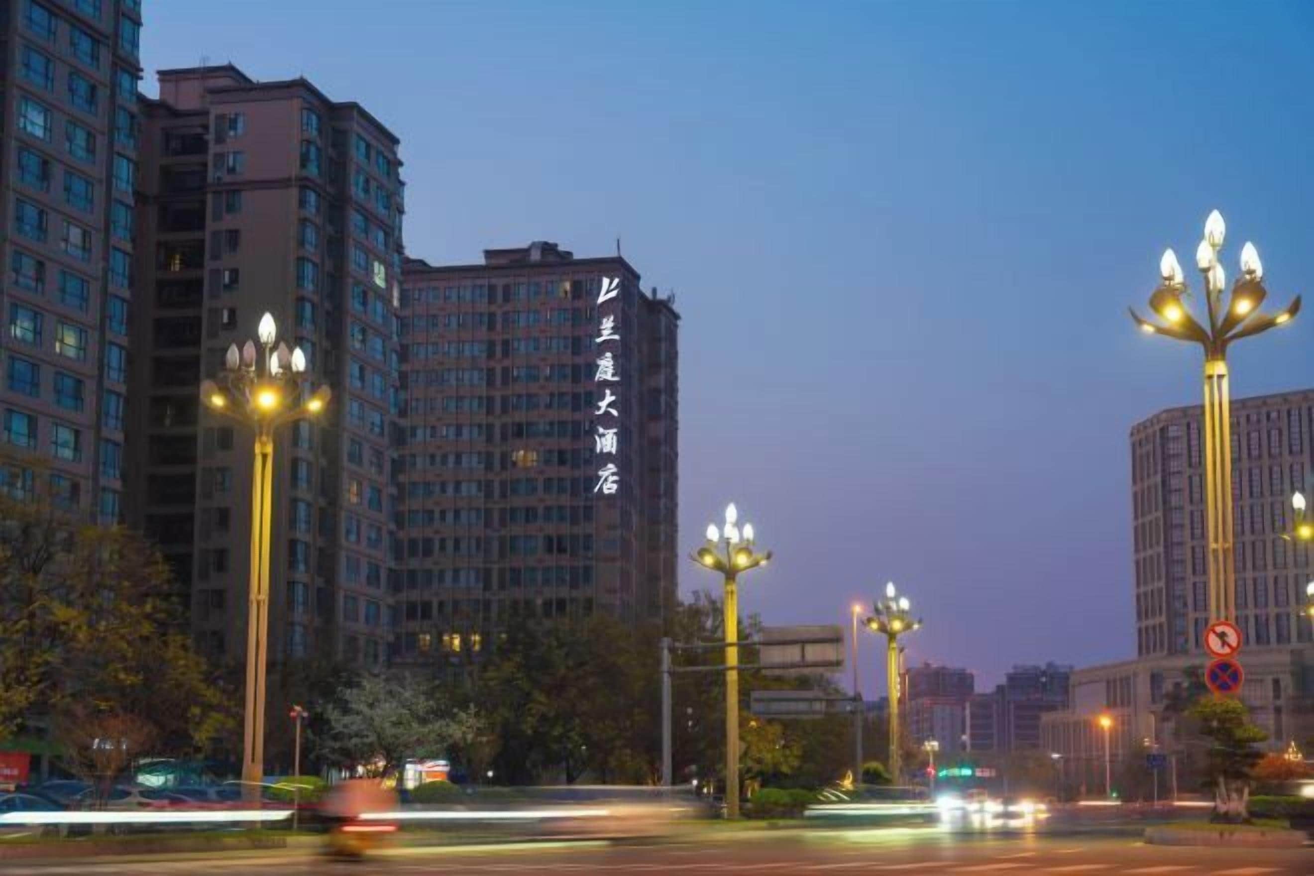 A multi-story building with illuminated signage, street lamps, and a clear sky.