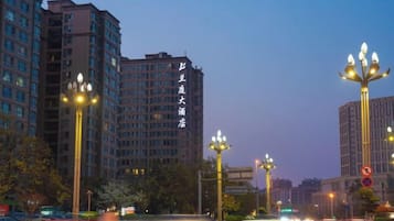 A multi-story building with illuminated signage, street lamps, and a clear sky.