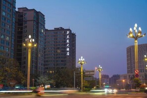 A multi-story building with illuminated signage, street lamps, and a clear sky.