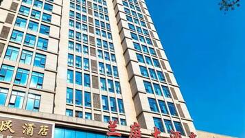 Un edificio de hotel moderno con varios pisos y un cielo azul despejado.