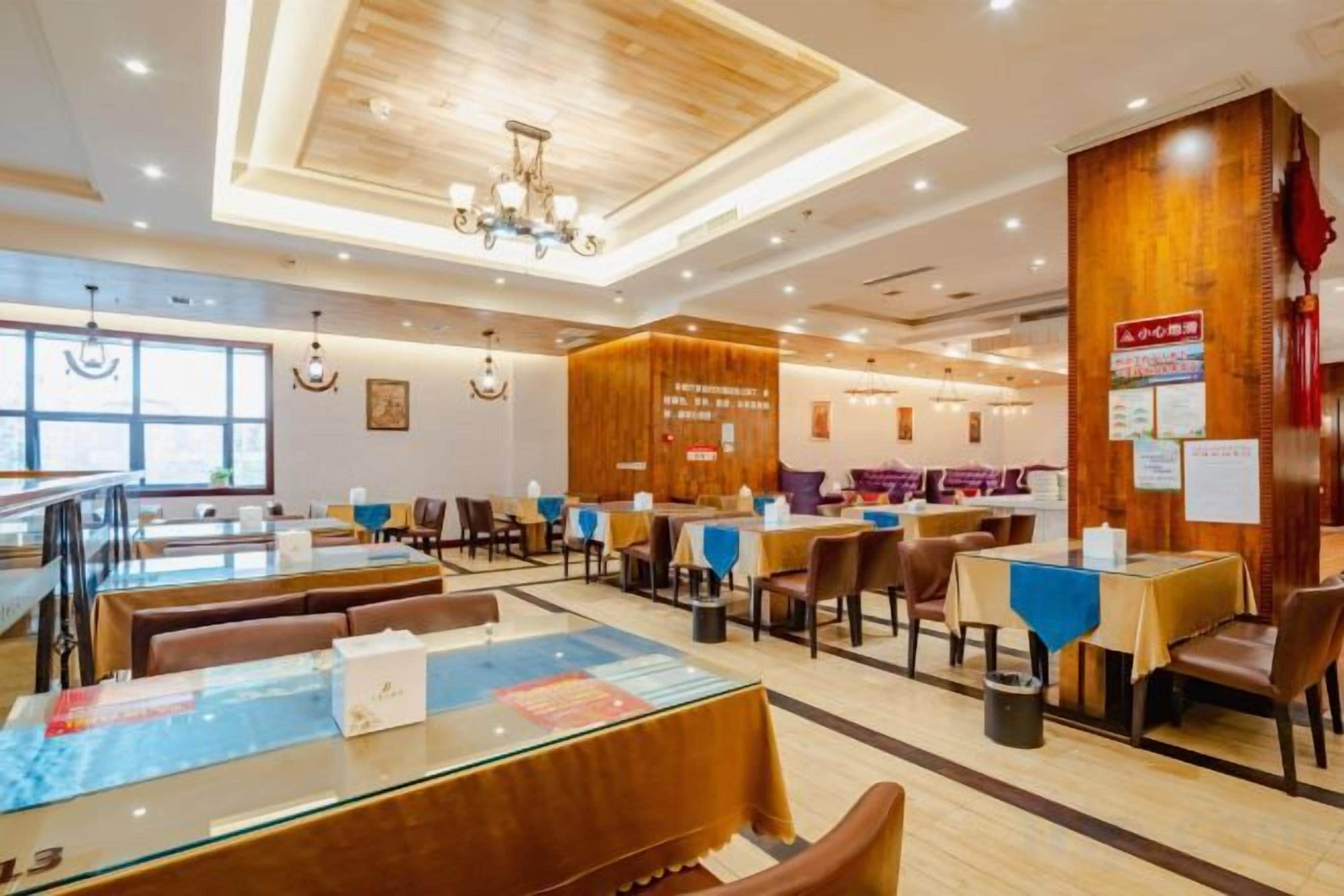 A restaurant with multiple dining tables and chairs, a wooden ceiling, and a view of the outside.