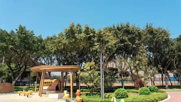 Un parque con un pabellón de madera, bancos y un área de juegos.