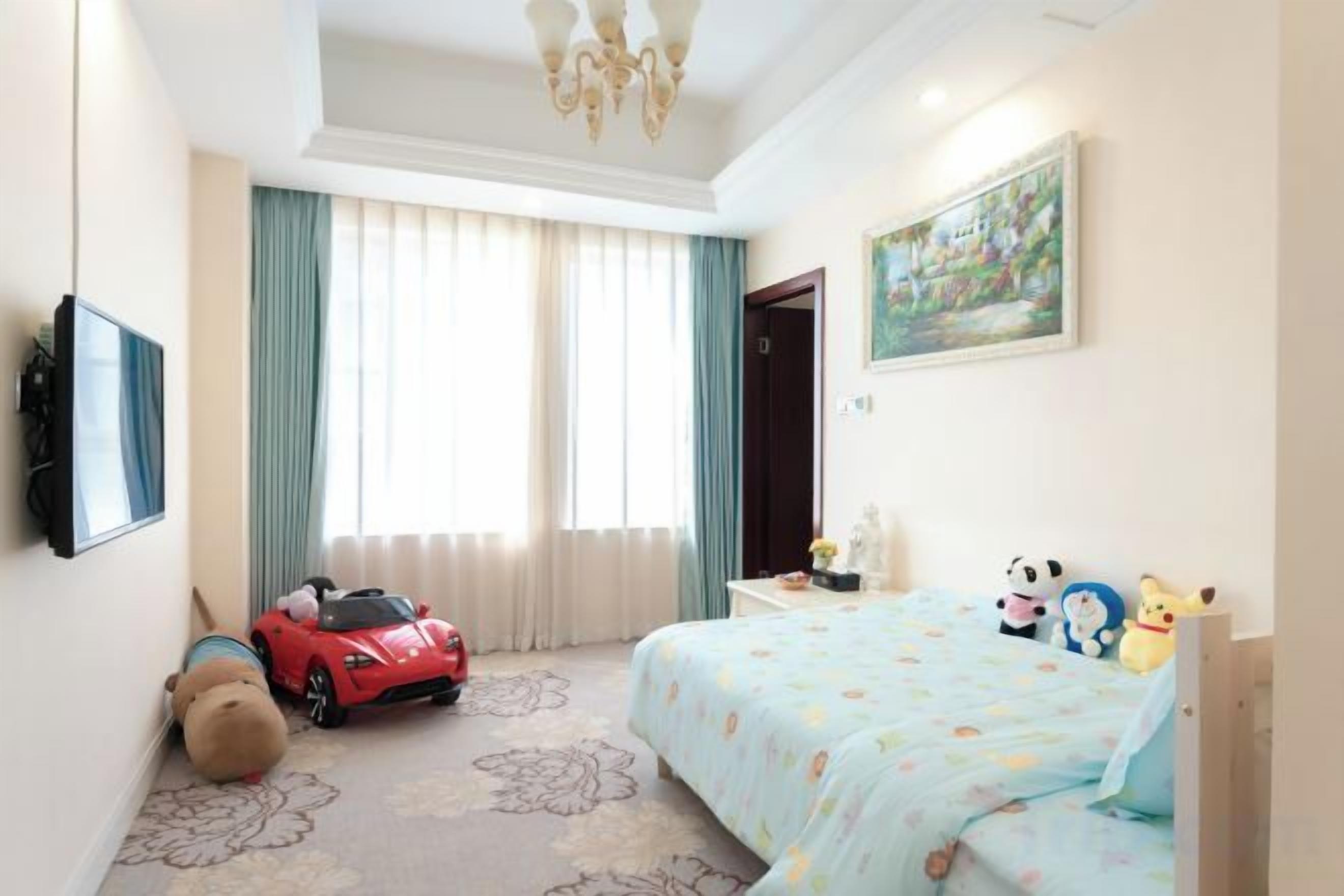 Una habitación de hotel con una cama, un televisor, un ventanal con cortinas y un coche de juguete.