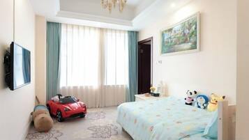 Una habitación de hotel con una cama, un televisor, un ventanal con cortinas y un coche de juguete.