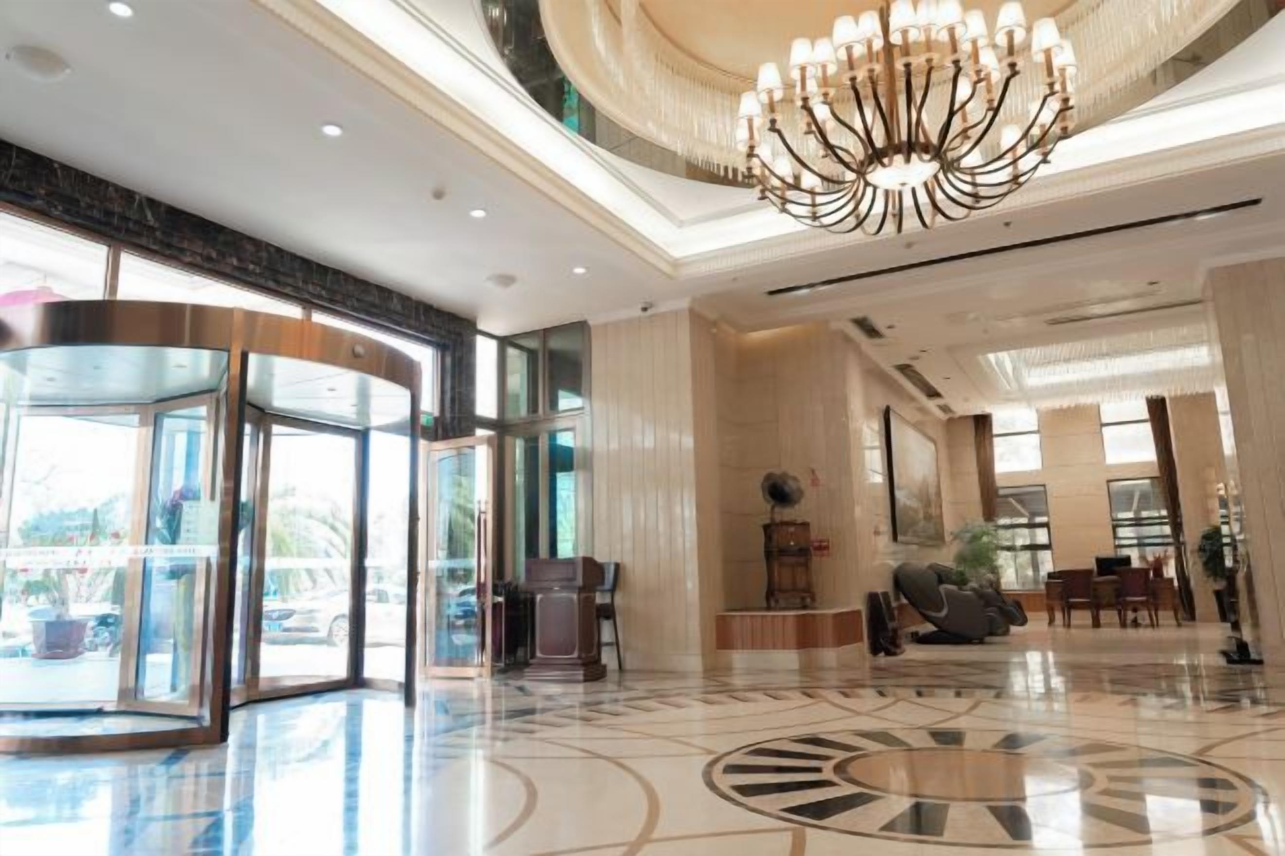 A hotel lobby with a revolving door, a chandelier, and a reception desk.
