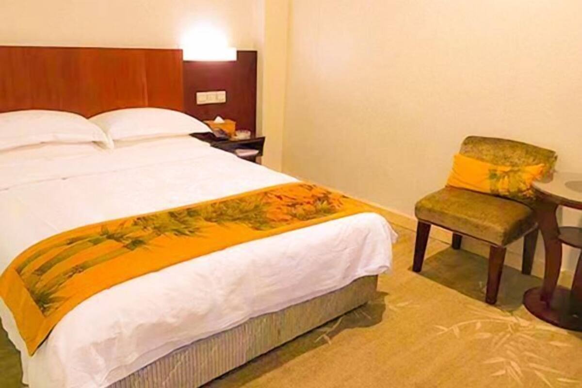 Ein Hotelzimmer mit einem Bett, einem Nachttisch, einem Sessel und einem kleinen Tisch.