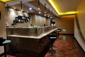 A bar area with a counter, stools, hanging lights, and shelves with items. - Cuizhu Hotel (Shenzhen)