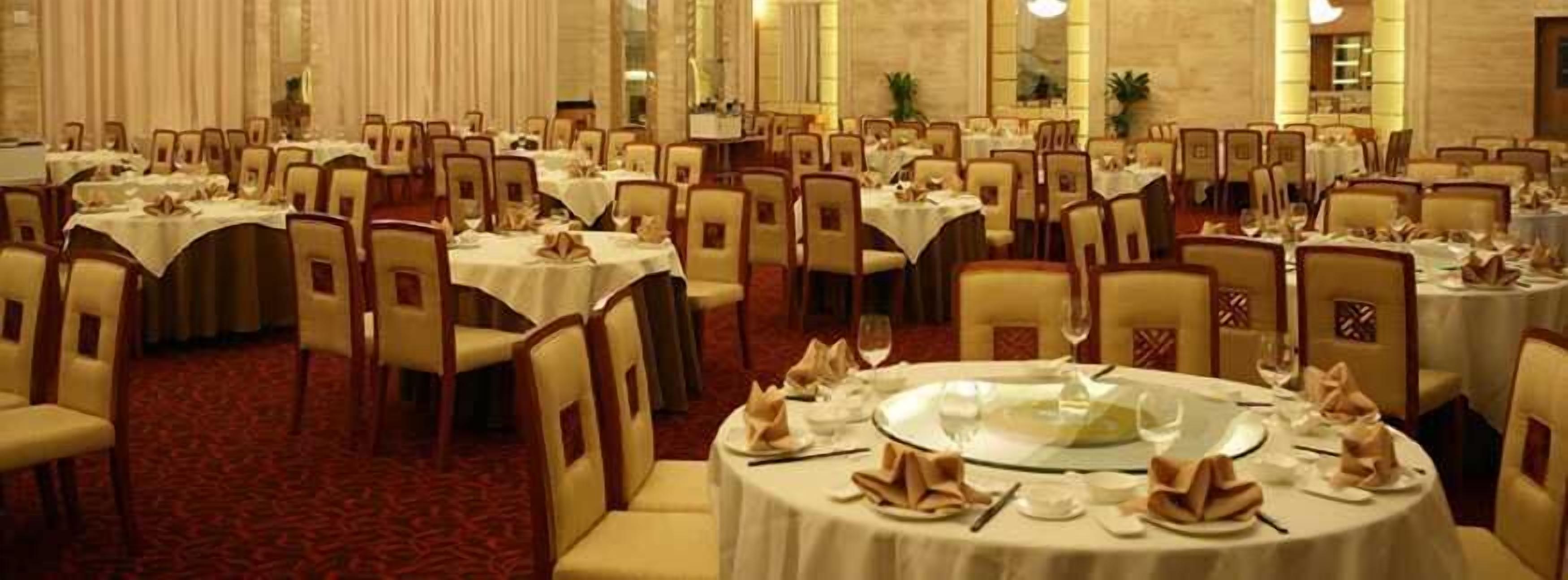 A banquet hall with round tables, chairs, and a carpeted floor.