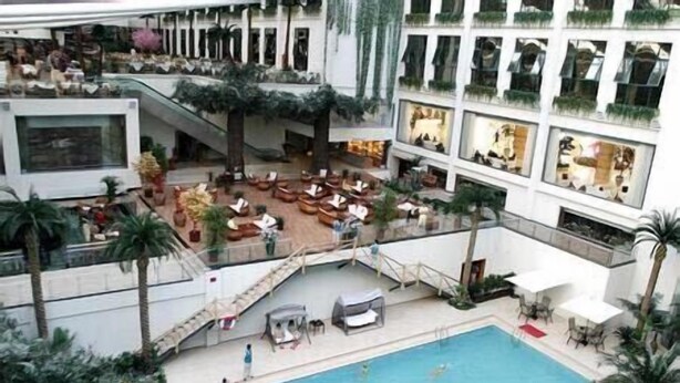 A multi-level hotel with a central pool area, outdoor seating, and indoor dining. - Hot Spring Hotel (Beijing)