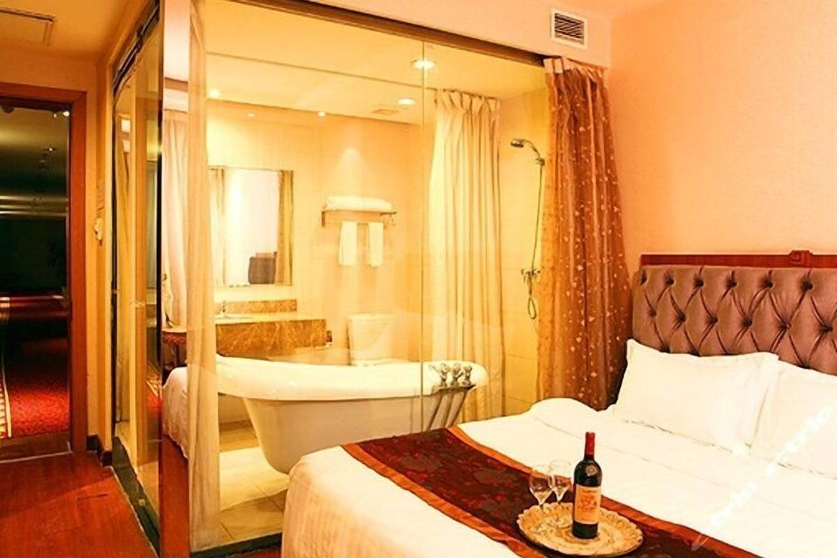 Una habitación de hotel con cama, baño con bañera y ducha.