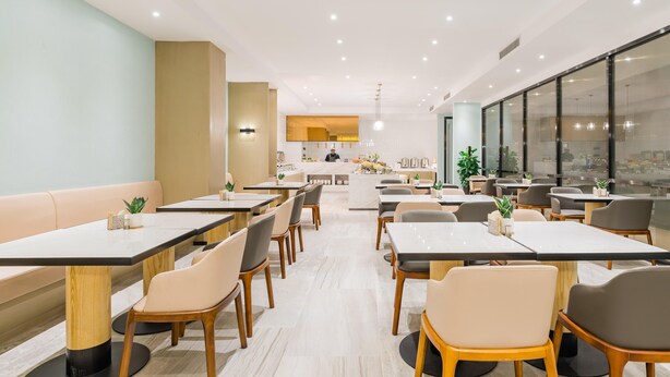 A modern dining area with multiple tables and chairs, a central island with a bar, and large windows providing natural light. - Atour  Light Hotel Hongqiao Beixinjing Metro Station Shanghai (Shanghai)