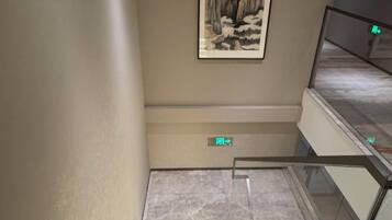 A staircase with a handrail, a wall-mounted artwork, and a digital display.