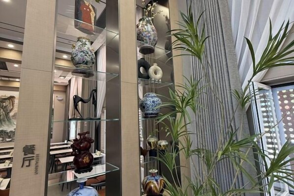 A modern interior with a glass display of decorative items, a vertical striped wall, and a plant. - Hejia Inn (Beijing Tsinghua) (Beijing)