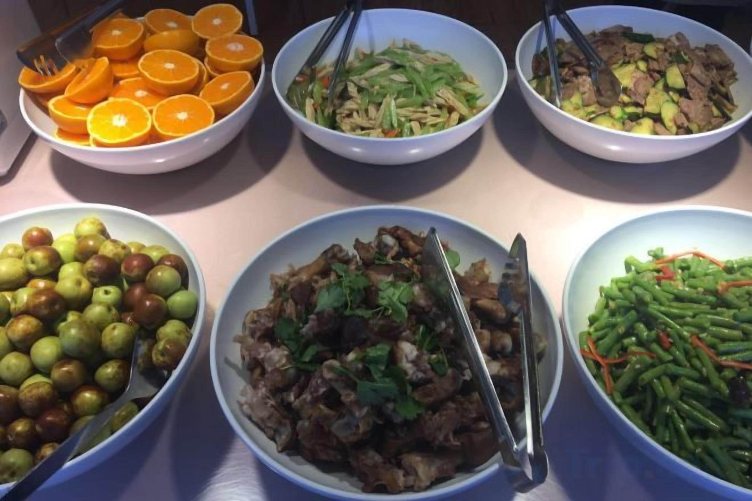 A table with various dishes including fruits, vegetables, and meat.
