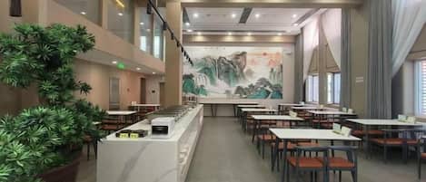 A restaurant with a long counter, multiple tables, and potted plants.