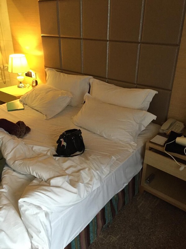 A hotel room with a bed, pillows, a bedside lamp, a nightstand, a phone, and a bag. - Funiton Hotel (Chengdu)
